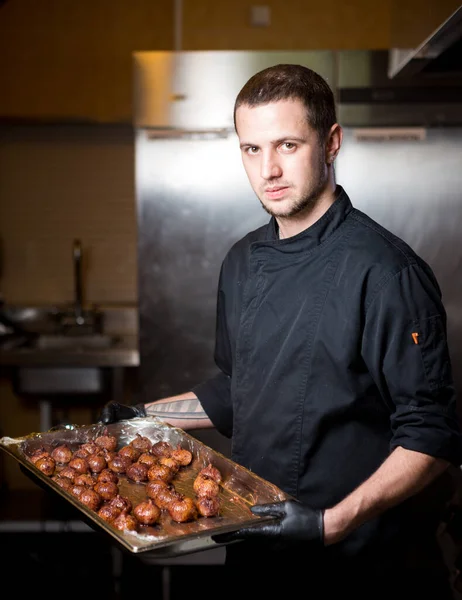 Portrait male chef with cooked food standing in kitchen. Theme cooking. young Caucasian man in black uniform, latex gloves at restaurant in kitchen. dish of figs, fig fruit fig tree or Ficus Carian — Stock Photo, Image