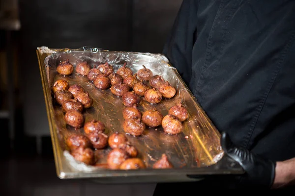 Portret mannelijke chef-kok met gekookt eten in de keuken. Themakoken. Jonge blanke man in zwart uniform, latex handschoenen in restaurant in keuken. schaal van vijgen, vijgenfruitvijgenboom of Ficus Carian — Stockfoto