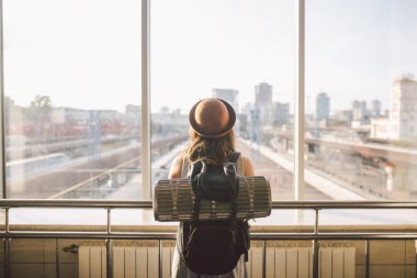 Seyyah Arka Görüş: Koridordaki tren istasyonunun penceresinde duran kadın. Sırt çantası, seçici odak, seyahat konsepti. Ulaşım konsepti. Tema seyahati toplu taşıma