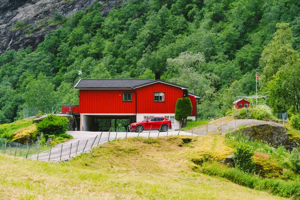 Červený dřevěný dům a auta v norském městě Flam. Venkovský dům a auto na dvoře. Chaty v horách. — Stock fotografie
