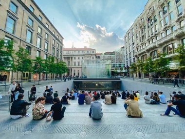 25 Eylül 2019 İtalya. Milan mı? Milano 'daki elma dükkanının yakınındaki merdivenlerde bir sürü insan oturuyor. Merdivenlerde, Milano 'daki Piazza Liberty logosundaki Apple Store' un kristal paralelliğine hayran kaldım.