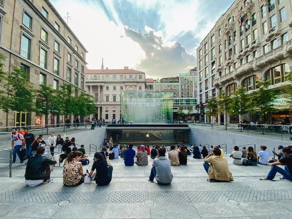 25. září 2019 Itálie. Milan. Spousta lidí sedí na schodech poblíž obchodu s jablky v Miláně. Na schodišti, obdivuje křišťálovou paralelu Apple Store v Piazza Liberty v Miláně logo jablko — Stock fotografie