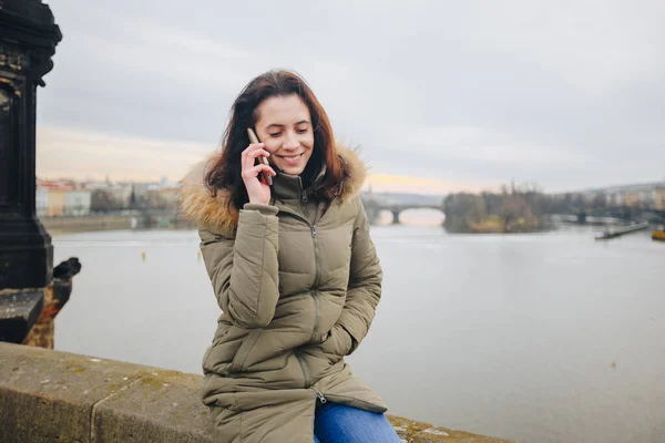 Mulher turista sorridente em Praga falando no smartphone. Jovem turista fica na Ponte Charles em Praga, na República Checa usa telefone — Fotografia de Stock