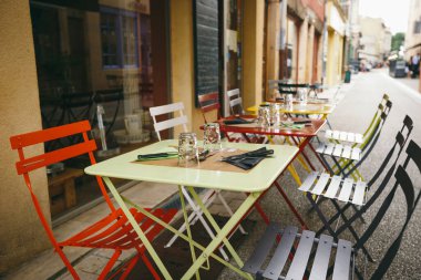 Temalı kafe ve restoranlar. Fransa 'da Avrupa' daki sokak kafeteryalarının parlak renklerinden oluşan dış yaz terası. Masaları korudum. İnsanlar olmadan, masalarda kimse olmadan..