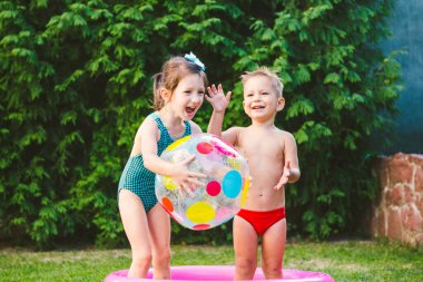 Çocuk oyunları için oyuncak. Şişme plastik plaj topuyla oynayan çocuklar. Su havuzunda. Yaz tatili. Oğlan ve Kız Şişme Havuz Bahçesinde Oynuyor. Çocuklar yaz bahçesinde eğleniyor..