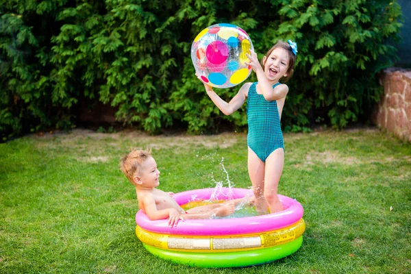 Inflatable Pool. Summer vacation concept. Games in water. Leisure in back yard. children bathing in an inflatable outdoor swimming pool and play Color Beach Ball. Healthy children summer activity.