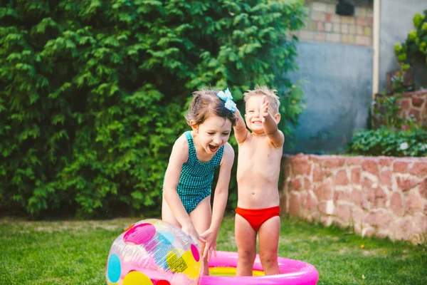インフレータブル プール 夏休みのコンセプト 水の中のゲーム 裏庭でのレジャー 子供たちは膨脹可能な屋外スイミングプールで入浴し カラービーチボールを再生します 健康な子供の夏の活動 — ストック写真