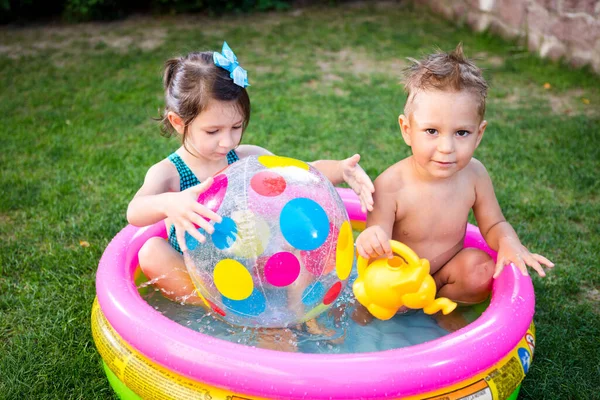 子供ゲームのためのおもちゃ 子供たちはインフレータブルゴムビーチボールで遊んでいます 水のプールで 夏休みだ 少年少女はインフレータブルプール裏庭で遊んでいます 夏の庭で外で遊んでいる子供たち — ストック写真