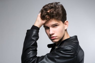 Genç moda adamı elini saçlarının arasından geçiriyor. Saçlı, erkek manken. Erkek Saçlı Güzel. Yakışıklı Erkek Manken Sağlıklı Saçlara Dokunuyor. Gri arka planda poz veren şık bir adam..