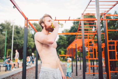 Sporcu yoğun egzersizden sonra dinleniyor, su içiyor. Genç ve güçlü sporcu erkek, spor yaparken şişeden su içiyor. Vücut sıvısına dikkat et. spor ve sağlık.