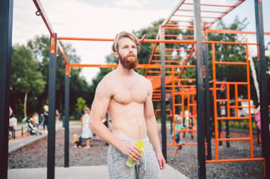 Spor salonundaki antrenmandan sonra spor şişesinden su içen kaslı bir adam. Açık hava eğitiminden sonra susamış bir adam su içiyor. Fitness, spor, yaşam tarzı konsepti. Susuz kalma ve sağlıklı kal..