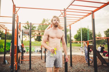 Spor salonunda su içen kaslı bir adam. Egzersiz yüzünden susuzluk ve susuzluk ve çok fazla terleme. Spor antrenmanından sonra yorgun erkek sporcu su içiyor. Fitness adamı mola veriyor..