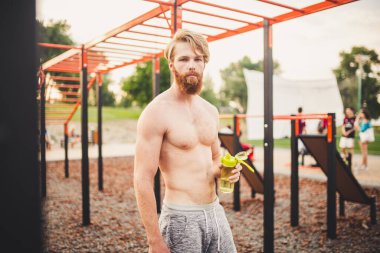 Spor salonunda su içen kaslı bir adam. Egzersiz yüzünden susuzluk ve susuzluk ve çok fazla terleme. Spor antrenmanından sonra yorgun erkek sporcu su içiyor. Fitness adamı mola veriyor..