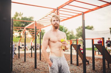 Spor salonunda su içen kaslı bir adam. Egzersiz yüzünden susuzluk ve susuzluk ve çok fazla terleme. Spor antrenmanından sonra yorgun erkek sporcu su içiyor. Fitness adamı mola veriyor..