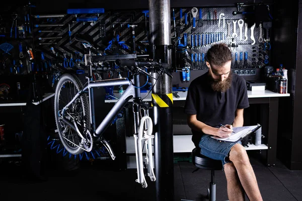 Stylowy Mechanik Rowerowy Robi Notatki Schowku Warsztacie Tematyczne Małych Przedsiębiorstw — Zdjęcie stockowe