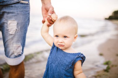 Babası deniz kenarındaki kumlu bir sahilde küçük kızının elini tutmasını öğretiyor. Baba ve kızı kıyı boyunca yalınayak yürür. Babalık ve çocukluk. Babalar Günü..