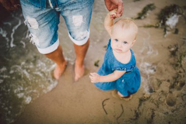 Babası deniz kenarındaki kumlu bir sahilde küçük kızının elini tutmasını öğretiyor. Baba ve kızı kıyı boyunca yalınayak yürür. Babalık ve çocukluk. Babalar Günü..