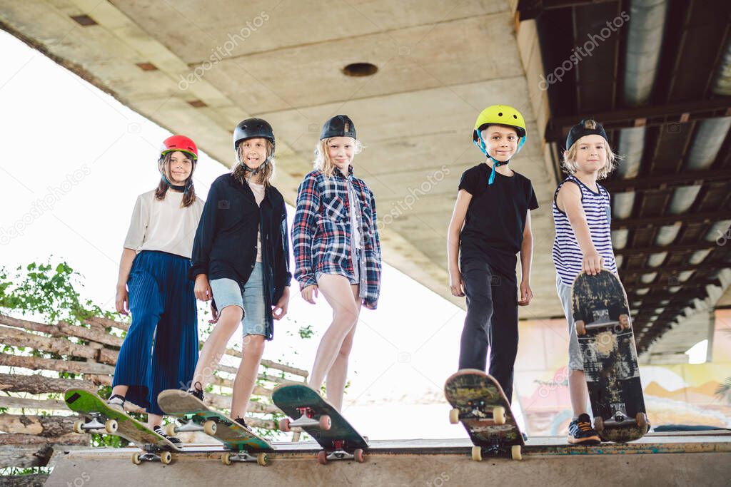 Extreme sport in city. Skateboarding Club for children. Group friends posing on ramp at skatepark. Early adolescence in skate training. Friends skateboarders on street platform for skating on board.