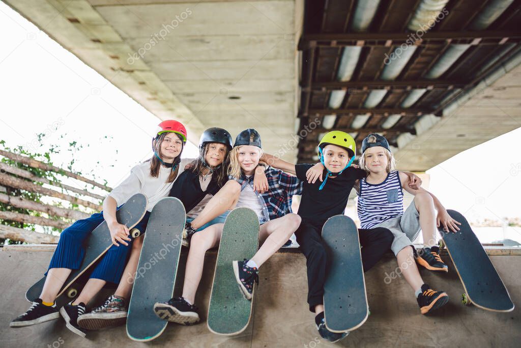 Extreme sport in city. Skateboarding Club for children. Group friends posing on ramp at skatepark. Early adolescence in skate training. Friends skateboarders on street platform for skating on board.