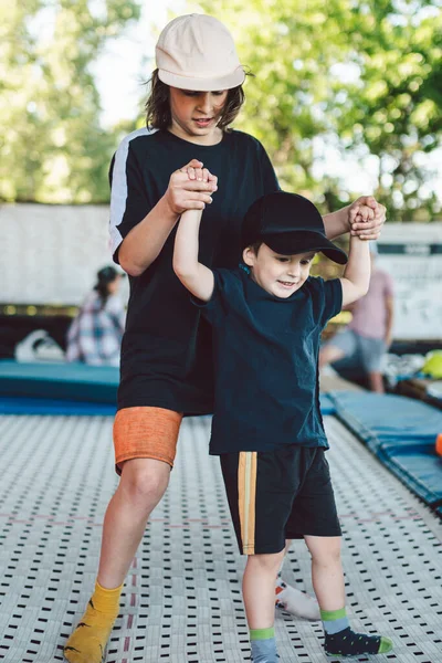 Der Große Bruder Lehrt Die Jüngeren Auf Einem Trampolin Springen — Stockfoto