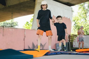 Spor merkezinde trambolinde zıplayan iki küçük çocuk. Çocuklar birlikte eğleniyor. Aktif boş zaman. Çocuklar trambolinde eğleniyor eğlence merkezinde, çocuklukta ve sportif yaşam tarzında.