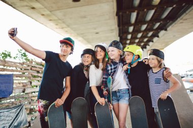 Büyük grup arkadaşları kaykaycılar video, online yayınlar, kaykay parkında telefonla video görüşmeleri yapıyorlar. Çocuklar kaykay antrenmanında zaman geçirir, selfie çekerler, birbirlerine sarılırlar..