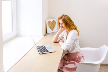 Ofiste dizüstü bilgisayar kullanan güzel bir genç kadın, daktilo, öğrenme, web siteleri, video görüşmeleri, müşteri danışmanlığı, uzak çalışma. Serbest ve yönetim. E ticaret, eğitim, İnternet teknolojisi.