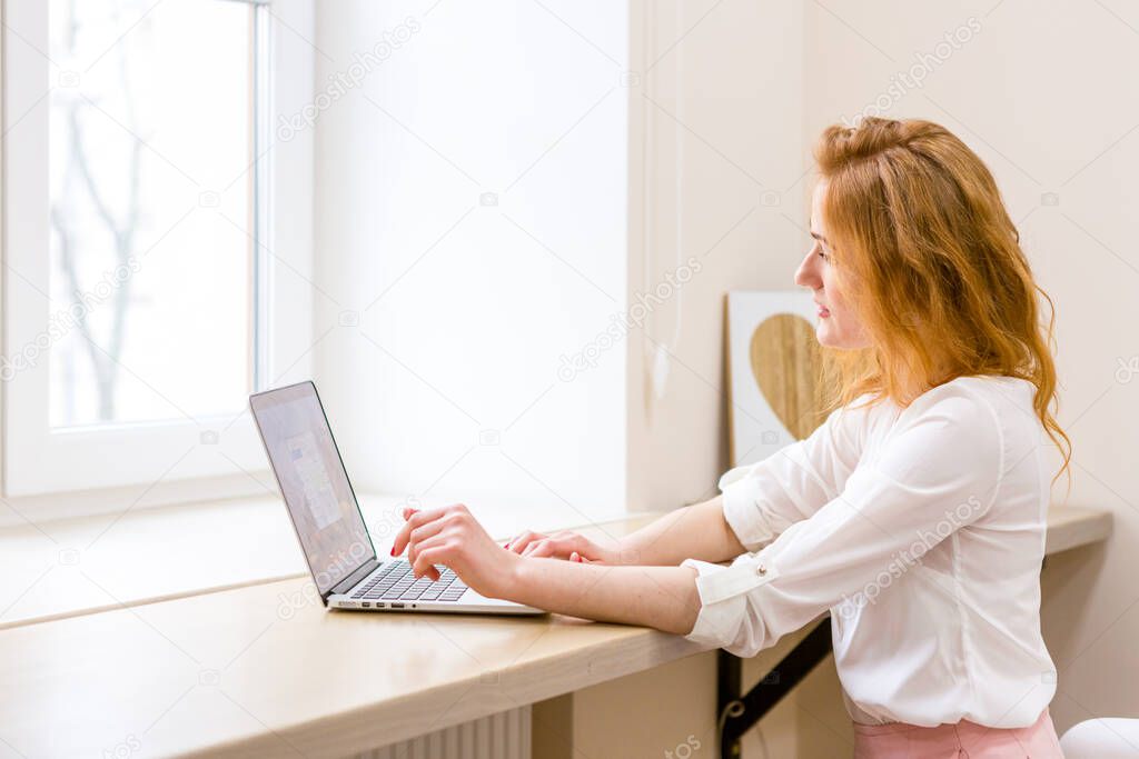 Beautiful young woman using laptop in office, typing, learning, watching webinars, video call, client consultations, distant work. Freelance and management. E commerce, education, Internet technology.
