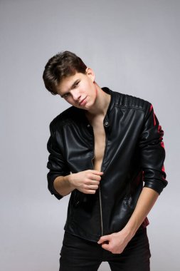 Yakışıklı, güzel bir erkek manken portresi. Deri ceket giyiyor. Deri ceketli ve kot pantolonlu bir adam. Stüdyoda genç seksi eşcinsel. Lgbt cemaati, duvara karşı poz veren gay adamın portresi..