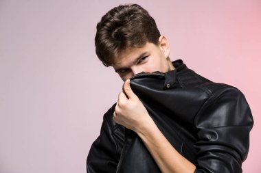 Çıplak Gövde 'de Deri Ceket Giyen Yakışıklı Atletik Erkek Model. Stüdyoda kırmızı arka planda motosikletli ceketli güzel vücutlu seksi bir genç. Deri ceketli şık genç adam..