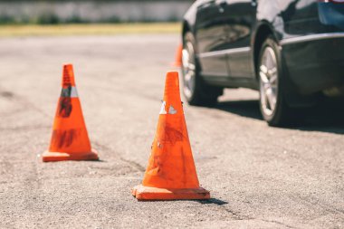 Araba ve trafik konileri, sürüş okulu konsepti. Araba sürme eğitimi için eski turuncu plastik koni, Oto-odrom 'da aşırı sürüş okulu. Güvenli sürüş eğitimi için stadyum. Okul eğitim arabası..