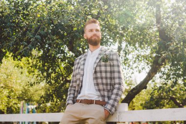 Zarif takım elbiseli seksi, yakışıklı, erkek modelin portresi. Zarif damat. Metroseksüel. Sakallı şık damat, bahçede damat. Güzel sanatlar. Köylü hipster portresi..