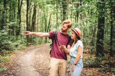 Ormanda gezinmek için akıllı telefon kullanan çift. Temalı turizm ve navigasyon, arama yolu, rota oluşturma, GPS telefon uygulaması. Yolu Bulmak İçin Akıllı Telefona Bakan iki kişi.