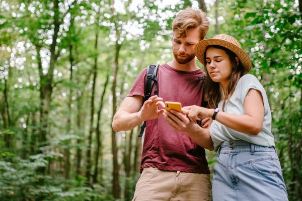 Hikers using mobile gps for directions. Happy couple checking smartphone in the woods during backpacking trip. Young joyful couple using gps map, navigator geolocation app. love and travel concept.