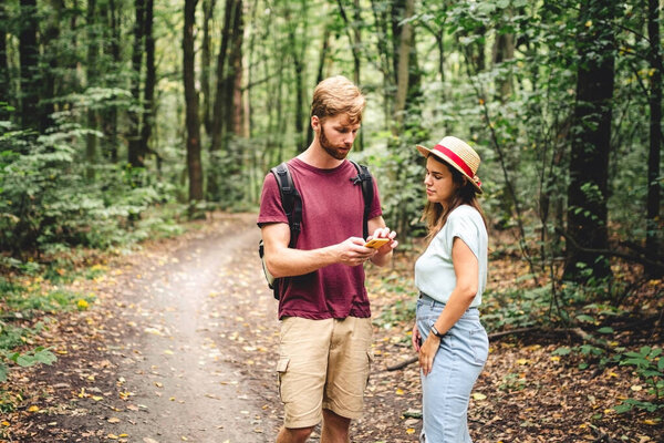 Hikers using mobile gps for directions. Happy couple checking smartphone in the woods during backpacking trip. Young joyful couple using gps map, navigator geolocation app. love and travel concept.