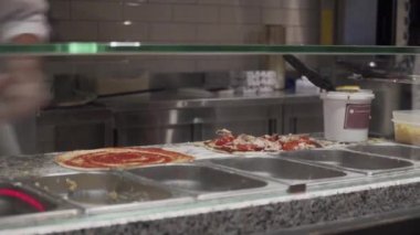 Fast food restoranındaki şefin elleri pizza görüntüsüne malzeme koydu. Pizza konsepti. Yiyecek üretimi ve teslimatı. Lezzetli, malzeme. 4K çözünürlükte vuruldu. İtalyan yemeği.