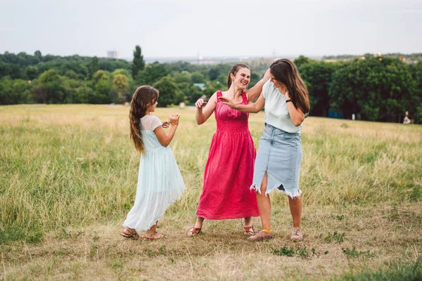 大人の白人姉妹3人がフィールドで遊んで楽しんでいます 3人の若い女性の家族が笑い 自然の中で夏の時間を過ごす 幸せな子供 お母さんと妹が走り 屋外で遊ぶ — ストック写真