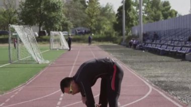 2 Mart 2019. Ukrayna, Kiev. Tema spor ve sağlık. Genç beyaz adam ısınmak için egzersiz yapıyor. Stadyum koşu bandında koşmadan önce ısınma kaslarını çalıştırıyor.