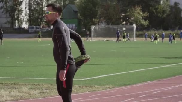 Le 2 mars 2019. Ukraine, Kiev. Thème sport et santé. Jeune homme caucasien fait de l'exercice échauffement étirement échauffement des muscles avant de s'entraîner à courir à un tapis roulant de piste de stade de la ville — Video