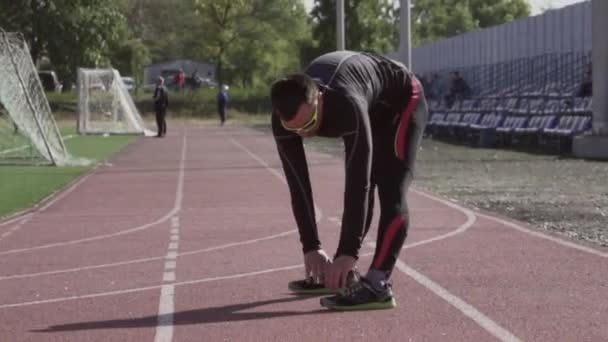 2019年3月2日。乌克兰，基辅。体育与健康主题。年轻的高加索人在城市体育场的跑步机上训练前，经常进行热身运动，以热身，热身肌肉 — 图库视频影像