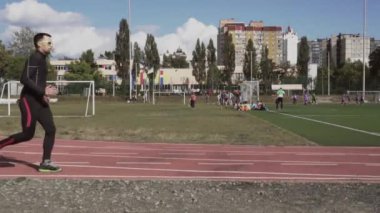 2 Mart 2019. Ukrayna, Kiev. Tema spor ve sağlık. Genç beyaz adam ısınma egzersizleri yapıyor. Stadyum koşu pistinde koşuyor.