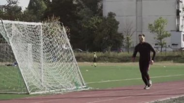 2 Mart 2019. Ukrayna, Kiev. Tema spor ve sağlık. Genç beyaz adam ısınma egzersizleri yapıyor. Stadyum koşu pistinde koşuyor.