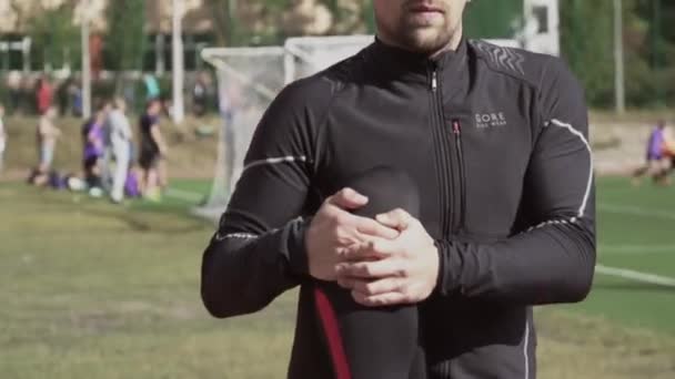 2019 년 3 월 2 일. 우크라이나, 키예프. 스포츠와 건강. 젊은 코카서스인 남자는 시 경기장 트랙 러닝 머신에서 달리는 훈련을 받기 전에 근육을 따뜻하게 하는 운동을 한다 — 비디오