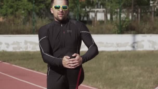 Le 2 mars 2019. Ukraine, Kiev. Thème sport et santé. Jeune homme caucasien fait de l'exercice échauffement étirement échauffement des muscles avant de s'entraîner à courir à un tapis roulant de piste de stade de la ville — Video