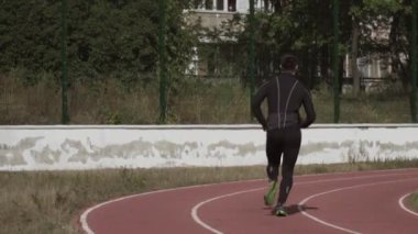 2 Mart 2019. Ukrayna, Kiev. Tema spor ve sağlık. Genç beyaz adam ısınma egzersizleri yapıyor. Stadyum koşu pistinde koşuyor.