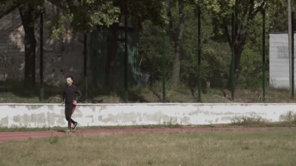 2 maart 2019. Oekraïne, Kiev. Themasport en gezondheid. Jonge Kaukasische man doet oefening warm up runs joggen in de stad stadion spoor loopband — Stockvideo