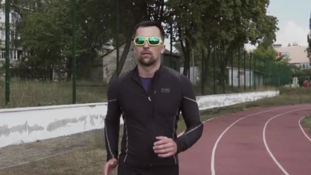 2019 년 3 월 2 일. 우크라이나, 키예프. 스포츠와 건강. 젊은 코카서스 남자는 도시 경기장 트랙 러닝 머신에서 조깅을 하며 몸을 따뜻하게 해 주는 운동을 한다 — 비디오