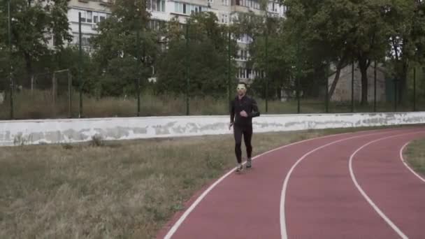 2 maart 2019. Oekraïne, Kiev. Themasport en gezondheid. Jonge Kaukasische man doet oefening warm up runs joggen in de stad stadion spoor loopband — Stockvideo