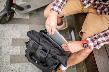 Yakışıklı hippi stili sakallı adam internette çalışıyor sırt çantalı, elektrikli scooterlı, aktif yaşam tarzlı, sırt çantalı gezgin. Ekoloji ve temiz ekolojik ulaşım biçimi.