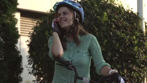 Πορτραίτο ενός χαρούμενου κοριτσιού που κρατάει κινητό τηλέφωνο. Ευτυχισμένος χαμογελαστός μαθητής χρησιμοποιώντας ποδήλατο κοινή χρήση app για έξυπνο τηλέφωνο εξωτερική. Πόλη τρόπο ζωής κομψό hipster κορίτσι με ποδήλατο χρησιμοποιώντας το smartphone app στο δρόμο — Αρχείο Βίντεο